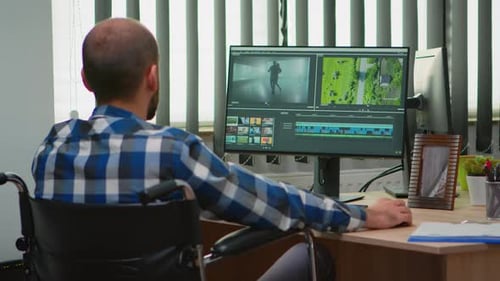 Man in Wheelchair Works at Computer in Office