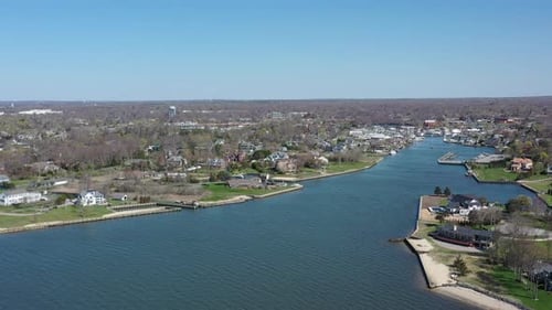An aerial view over Bay Shore, NY, on a sunny day with clear skies. The camera dolly in over the wat