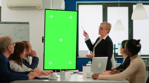 Team Leader Standing at Meeting Table Analysing Financial Statistics Looking at Green Screen Display
