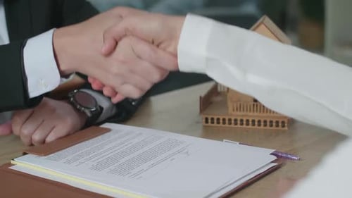 Close Up Of A Woman With Real Estate Agent Signing On House Purchase Contract Paper