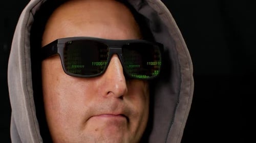 Green Binary Code Is Reflected in the Black Glasses of the Hacker's Glasses. Computer Hacker in
