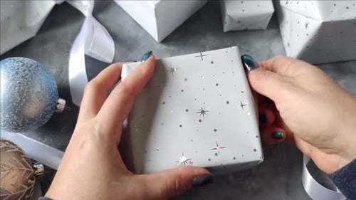 Hands Wrapping a Holiday Gift in Star Paper