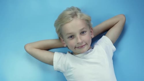 Portrait d'un garçon de huit ans couché sur fond bleu