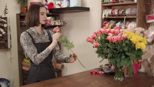 Florist Girl Is Making a Floral Arrangement From Fresh Roses in a Shop