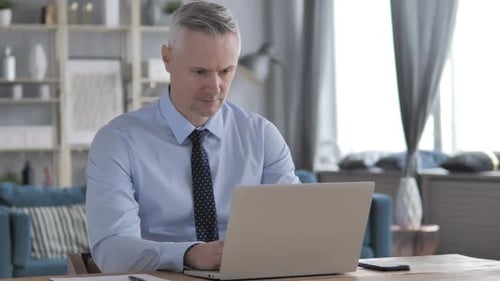 Man Works on Laptop at Home Office