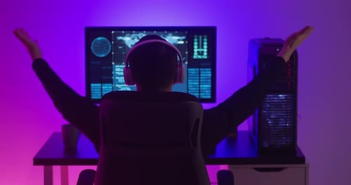 Man Programmer in Headphones Happy with Success While Working at a Computer in Data Center at Night