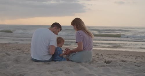 Young Parents Playing with Their Toddler Son on the Beach