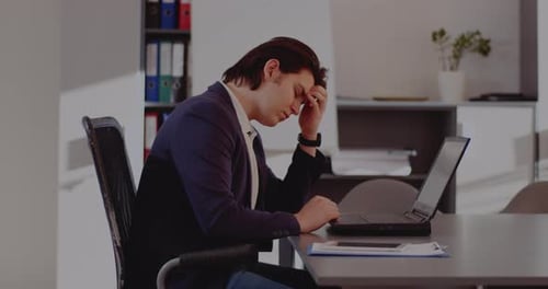 Tensed Businessman Using Laptop in Office