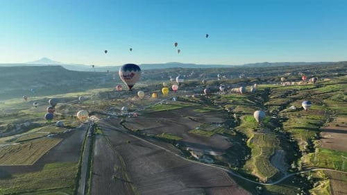 Hot air balloons fly over the mountainous landscape of Cappadocia, Turkey.