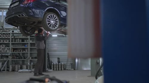 Mechanic Inspecting Car Undercarriage on Lift