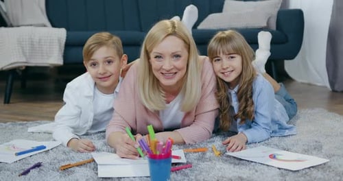 Blond Woman Drawing With Children on Floor