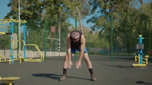 A Retired Elderly Man Works Out on a Sports Ground Outside. Healthy Lifestyle Concept