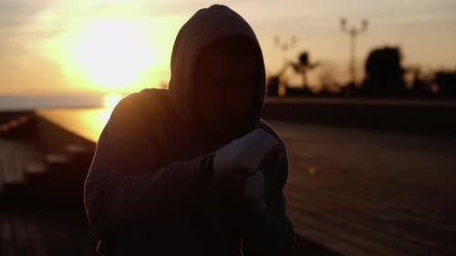 Hooded Boxer Shadow Boxing at Sunrise by Ocean