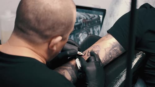 Male Tattoo Artist Tattooing a Client