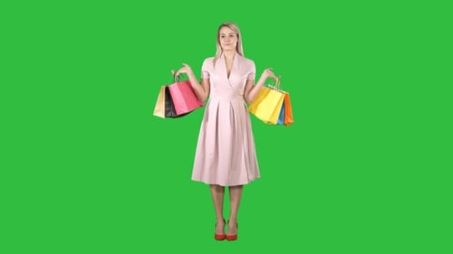 Woman with shopping bags in pink dress standing on a Green
