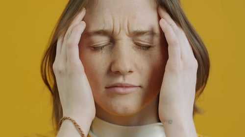 Woman Relieving Painful Headache With Hands on Temples