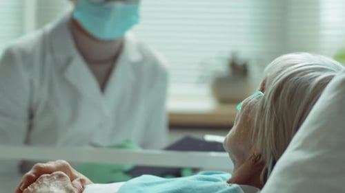 Healthcare Worker Visits Elderly Patient in Hospital Bed