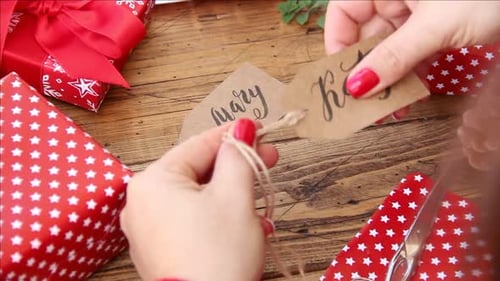 Woman Attaches Tag to Gifts on Table