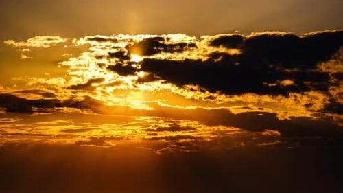 Sun Setting Behind Dark Clouds in a Golden Sky