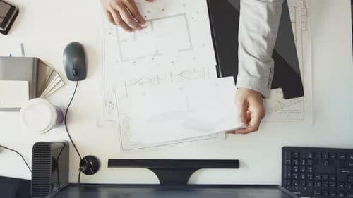 The Engineer Opens a Folder with Drawings and Works at the Table