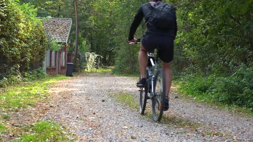 Ein Radfahrer fährt einen Pfad entlang durch eine ländliche Gegend - Rückansicht
