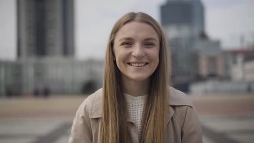 Portrait of Beautiful Young Caucasian Woman Standing in Urban City on Overcast Day and Smiling at