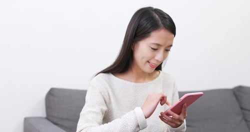 Woman Using Smartphone on Gray Couch Indoors