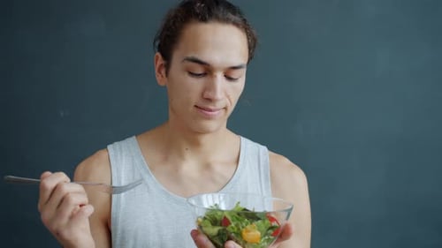Young Adult Man Holding Salad Bowl and Fork