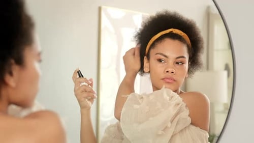 Stylish Woman Sprays Hair in Front of Mirror