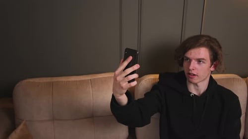 Young Adult Talks on Smartphone Video Call Indoors