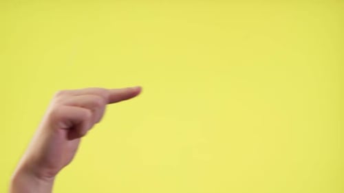 Close-Up Of Cropped Hand Pointing Finger Over Yellow Background