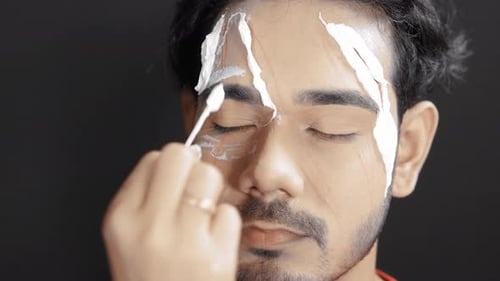Makeup Artist Applies Cream to a Man's Face