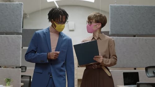 Two Multiethnic Colleagues Discussing Document in Office