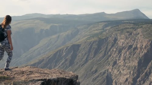 Happy Successful Girl Raises Her Hands Up on the Edge of a Cliff