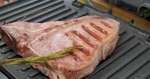Juicy Beef Steak with Rosemary is Cooked on an Electric Grill