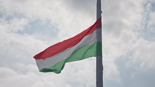 Hungarian Flag Waving on Pole Against Cloudy Sky