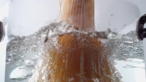 Camera follows cooking spaghetti noodles in boiling water. Slow Motion.