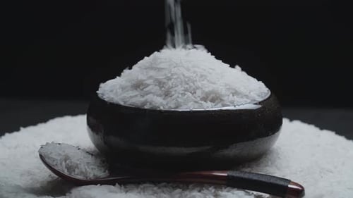 White Rice Being Poured Into a Black Bowl