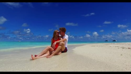 Family of two sunbathe on tranquil lagoon beach lifestyle by blue water and white sandy background o