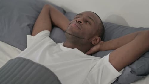 Homme africain couché dans son lit éveillé pensant