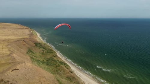 Atemberaubendes Meer und Himmel im Hintergrund eines in der Luft fliegenden Gleitschirms