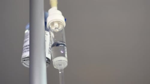 Close up of an antibiotic solution dripping through a medical patient's iv into a picc line during a