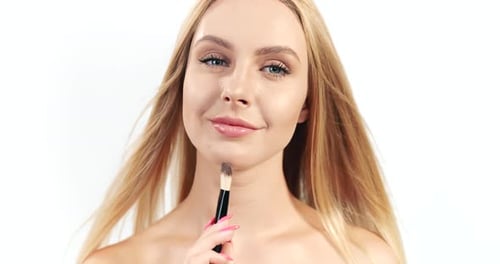 Blonde Woman Applies Makeup with Brush