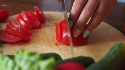 Woman Cuts Tomato on Wooden Cutting Board