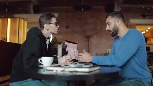 Adults Collaborating on Project Using Laptop in Workspace