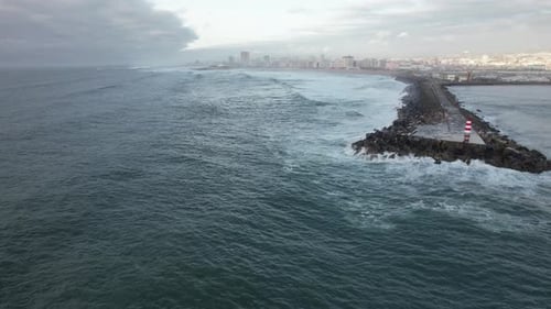 Waves Crashing on Rocky Coastline with Lighthouse