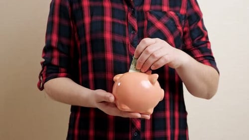 Woman Holds Piggy Bank on Palm and Throws Banknote Inside