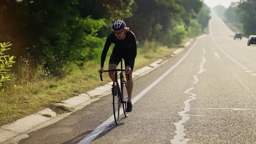 Radfahrer mit Helm fährt mit dem Fahrrad die Strecke entlang und gewinnt an Geschwindigkeit