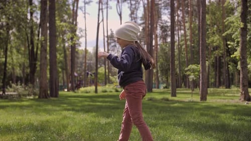 Carefree Girl Dancing and Spinning on a Green Meadow in the Park Late Afternoon