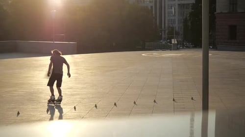Young Long-haired Bearded Man Roller Skater Is Dancing Between Cones in the Evening in a City Park